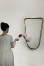 Surreal gesture of a hand coming out of the mirror to give a rose to a woman