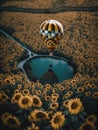 A surreal image of hot air balloon flying over a field of sunflowers with cmall round lake at center. AI generative