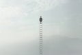 Man sitting on a very high ladder in the middle of nature