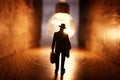 Surreal image of person in dark corridor looking at glowing light bulb. Concept of finding the right idea, or way out Royalty Free Stock Photo