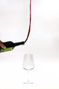 Surreal image of red wine pouring out of a bottle towards the top instead of the glass over white background Royalty Free Stock Photo