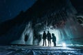 Surreal landscape with people exploring mysterious ice grotto cave. Outdoor adventure. Family exploring huge icy cave Royalty Free Stock Photo