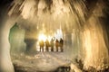 Surreal landscape with people exploring mysterious ice grotto cave. Outdoor adventure. Family exploring huge icy cave Royalty Free Stock Photo