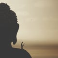 Surreal man meditates seated on top of a giant buddha illuminated by the light of dawn Royalty Free Stock Photo