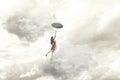 Surreal moment of an elegant woman flying in the middle of the clouds hanging on her umbrella