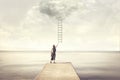 Surreal moment of woman climbing an imaginary scale to the clouds Royalty Free Stock Photo