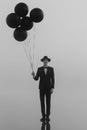 surreal portrait of a man in a suit with a hat with balloons in his hand on the water