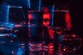 portrait of a strange man looking through glasses of water with blurring and red and blue neon lights