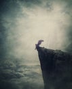 Surreal scene with an angel fallen in limbo, sitting alone on the edge of a cliff between the skies. Magical winged creature Royalty Free Stock Photo