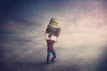 Surreal scene, angry student guy tired of constant learning, carrying huge heavy books pile over his head. Frustrated boy back to