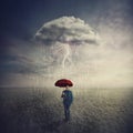 Surreal scene as man stands outdoors under umbrella due a single mysterious storm cloud raining only over him. Find solution to Royalty Free Stock Photo