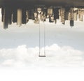 Surreal swing hanging upside down compared to the metropolis Royalty Free Stock Photo