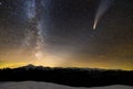 Surreal view of night in mountains with starry dark blue cloudy sky and C/2020 F3 NEOWISE comet with light tail Royalty Free Stock Photo