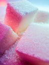 Heap of transparent white sugar crystals with large pieces of sugar in mixed colour light. Macro photo