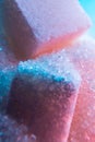 Heap of transparent white sugar crystals with large pieces of sugar in mixed colour light. Macro photo