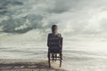 Surreal woman looks at the infinite sitting on a chair inside the sea