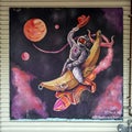 Surrealistic mural featuring a space cowboy painted on wood and hanging on an outside wall in Dallas, Texas.