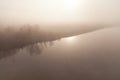 Foggy morning over the autumn river, no horizon, sun and shore line reflected in the water. Ukraine.