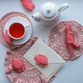 Surrealistic wonderland tea drinking - a mug with flavored pink tea, crocheted napkins, a teapot, toys - fish and dinosaur