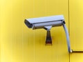 Surveillance camera on the exterior sandwich wall of a yellow building. Royalty Free Stock Photo