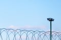 Surveillance cameras over barbed wire against a blue sky. Fenced guarded territory, no access. Area protection and counteraction