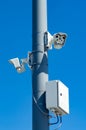 Surveillance cameras on a pole against a blue sky.