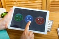 Woman choosing her opinion with smiley faces on touch screen