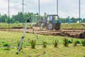 Surveying measuring equipment level theodolite stands on a tripod on a green lawn, in the background a tractor levels the ground Royalty Free Stock Photo