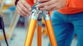 Surveyor adjusting orange tripod on construction site Royalty Free Stock Photo