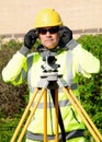 Surveyor using autolevel to check levels on new housing development during new road construction