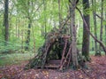 Survival shelter in the woods from tree branches. Cone or pyramid shape shelter