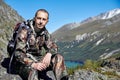 Survival in the wild. A man in camouflage resting among the mountains. Stalker, survive in the woods Royalty Free Stock Photo