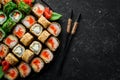 Sushi bar menu. Set of colored delicious sushi rolls on black plates. Royalty Free Stock Photo