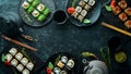 Sushi bar menu. Set of colored delicious sushi rolls on black plates. Royalty Free Stock Photo