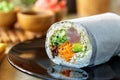 Sushi burrito roll on shiny black plate