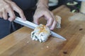 Sushi chef hand cutting a roll of sushi