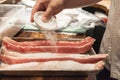 A sushi chef prepares fish with salt.