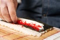 Sushi chef puts red masago caviar in a roll