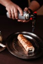 Sushi chef roasting a sushi set on an iron tray