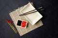 Sushi chopsticks, soy sauce, ginger, bamboo mat and empty plate on black background. Royalty Free Stock Photo