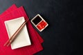 Sushi chopsticks, soy sauce, ginger, red bamboo mat and empty plate on black background.