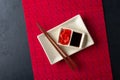 Sushi chopsticks, soy sauce, ginger, red bamboo mat and empty plate on black background. Royalty Free Stock Photo