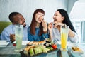 Sushi concept, seafood, asian meal. Three young multiethnic friends, Caucasian and Asian girls, African man, sitting in