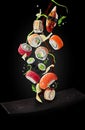 Sushi with garnishes and soy sauce hovering over plate on black background Royalty Free Stock Photo