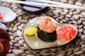 Sushi Gunkan maki with salmon on plate on bamboo mat decorated with flowers. Japanese cuisine. Royalty Free Stock Photo