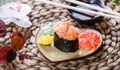 Sushi Gunkan maki with salmon on plate on bamboo mat decorated with flowers. Japanese cuisine. Royalty Free Stock Photo