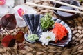Sushi Gunkan maki with seaweed, sesame and cream cheese on black plate on bamboo mat decorated with flowers. Japanese cuisine. Royalty Free Stock Photo