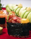 Sushi maki roll on red plate on white background. Macro close up of tuna tartare sashimi gunkan with raw quail egg and shiso leaf Royalty Free Stock Photo