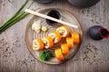 Sushi maki rolls with salmon, avocado, cucumber, flying fish roe on a plate with chopsticks, soy sauce, wasabi and Royalty Free Stock Photo