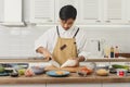 Sushi master chef making rolls on chopping board in the kitchen. Various ingredients around Royalty Free Stock Photo